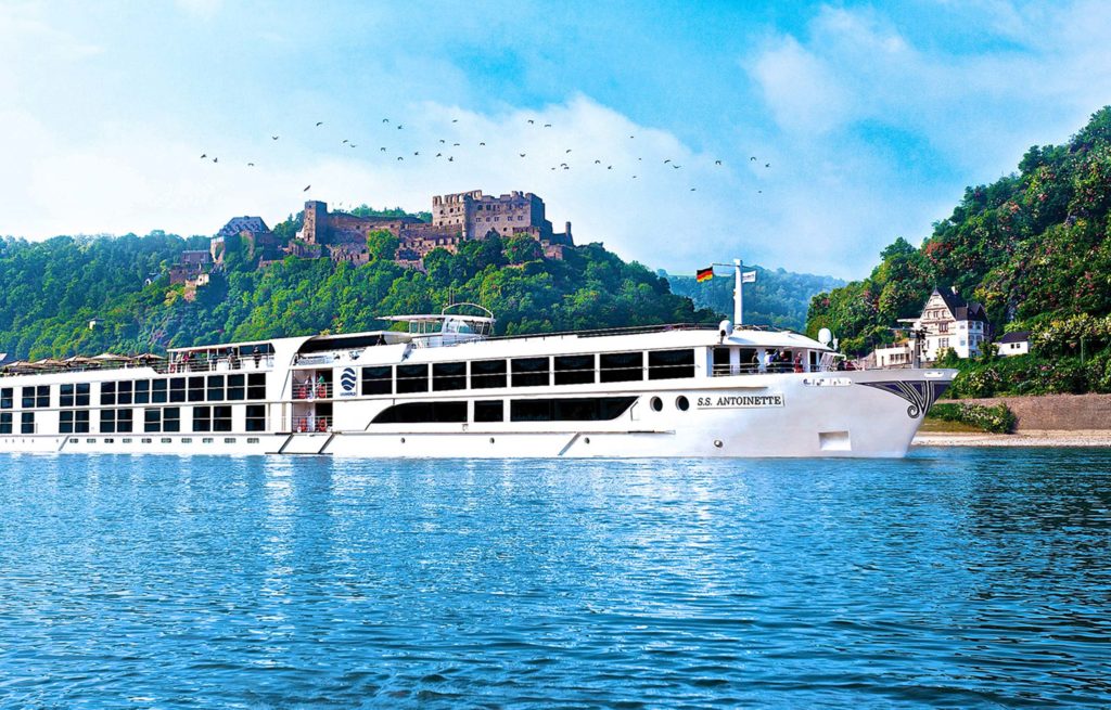 A large cruise ship on the water with a castle in the background.