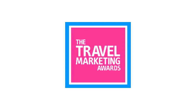 A square logo with a pink background and blue border displaying the text "The Travel Marketing Awards" in white capital letters.